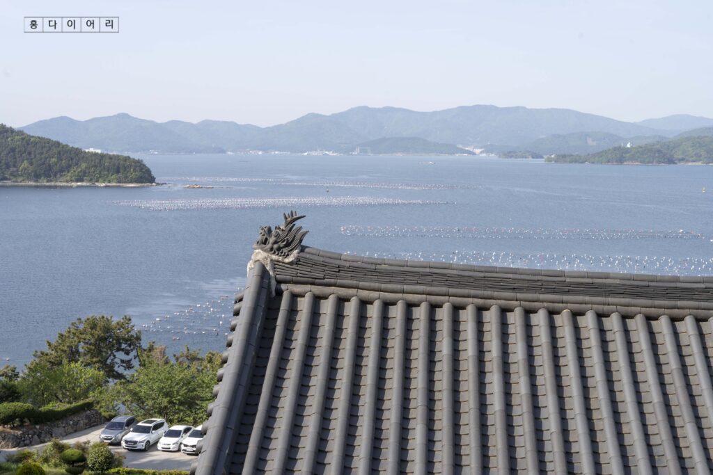 長水庵の屋根越しに広がる馬山湾の海景色