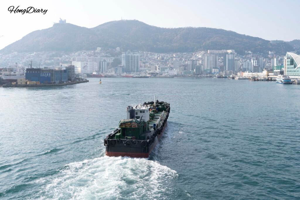 Cargo ship passing through Yeongdo waterfront with Busan city in the background