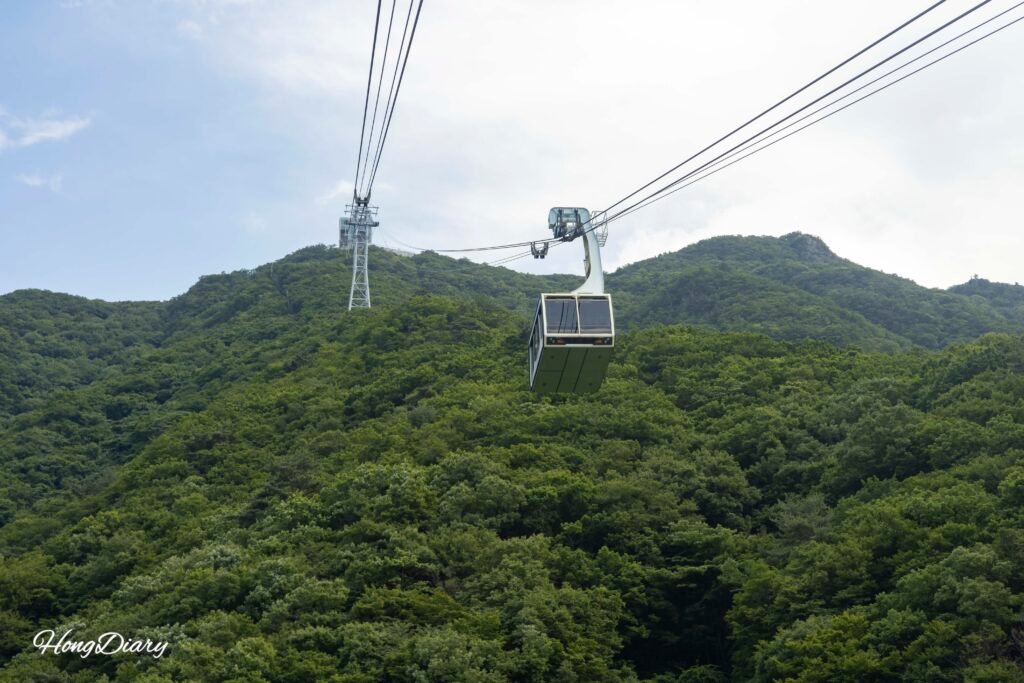 Cabina del teleférico Valle del Hielo Miryang subiendo entre la vegetación hacia los Alpes de Yeongnam