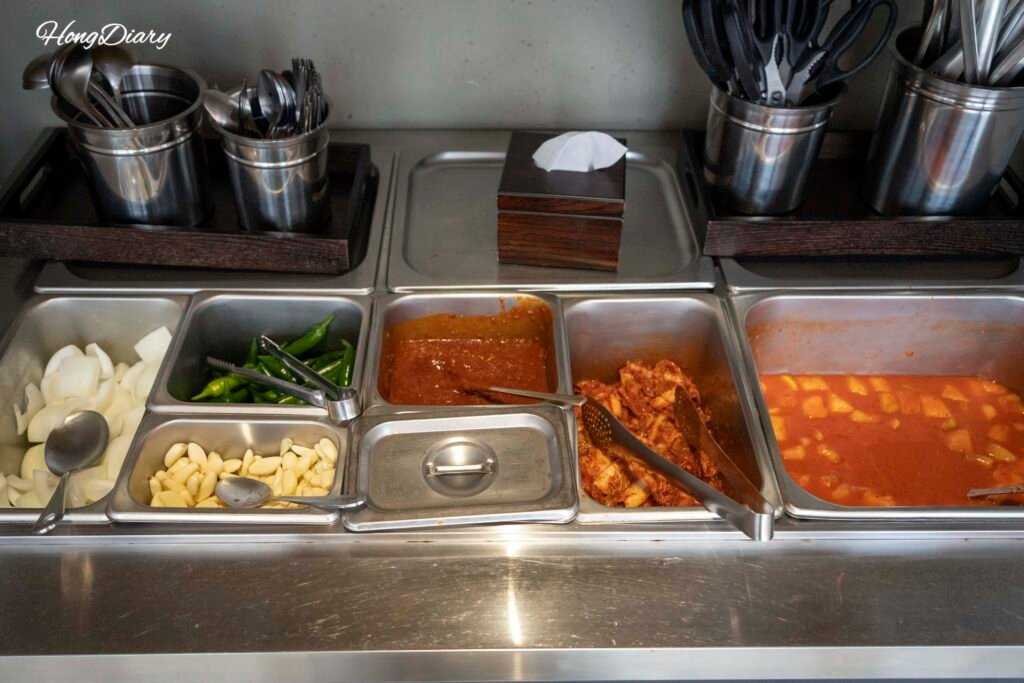 Self-service side dish station at Jeongjitgan Busan with kimchi and condiments