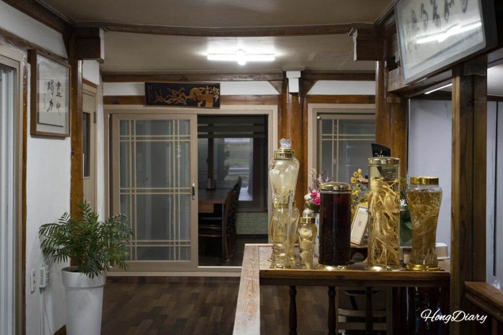 江辺ガーデンの店内と大きな人参酒のボトル｜錦山