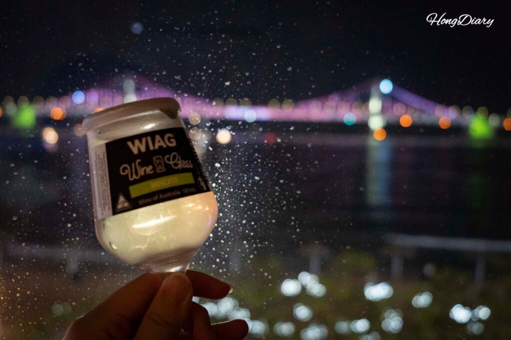 Glass of wine by the window with Gwangan Bridge night view from the ocean view room at Gwangalli W Hotel, Busan