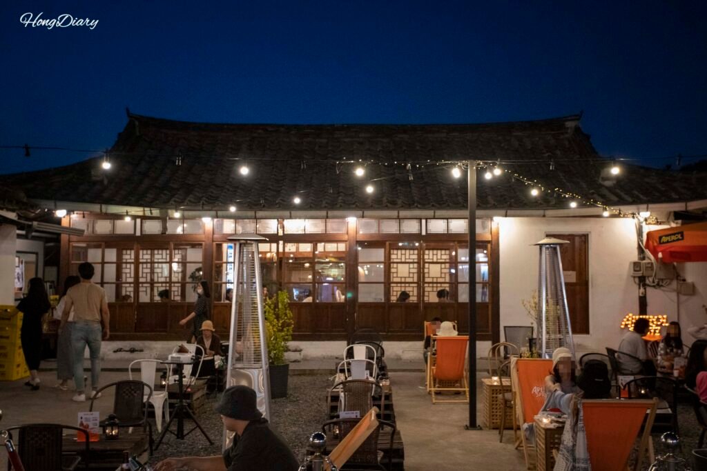 Callejón iluminado de noche en Hwangnidan-gil, Gyeongju, con fachadas hanok y visitantes