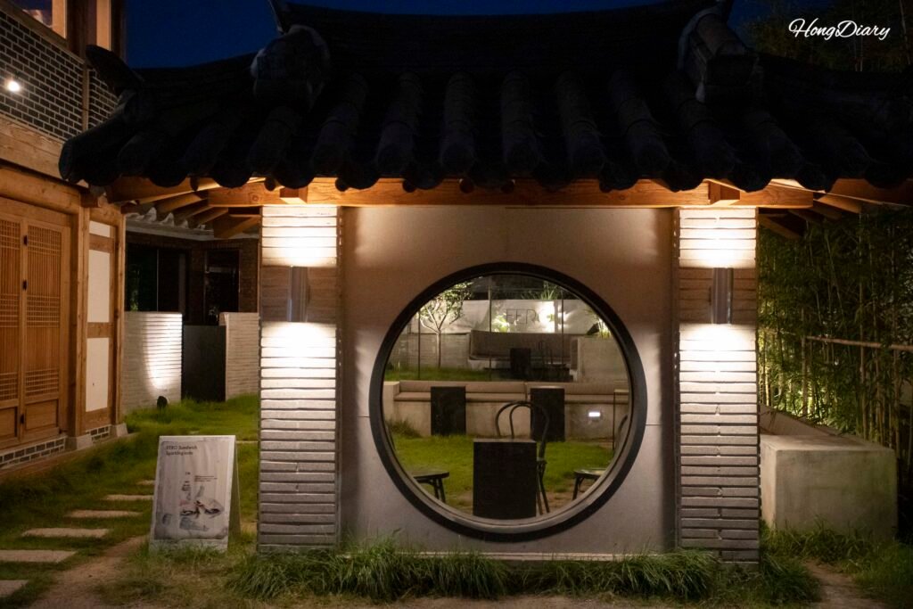 Tiendas iluminadas de noche en Hwangnidan-gil, Gyeongju, con luz cálida reflejada en techos de teja
