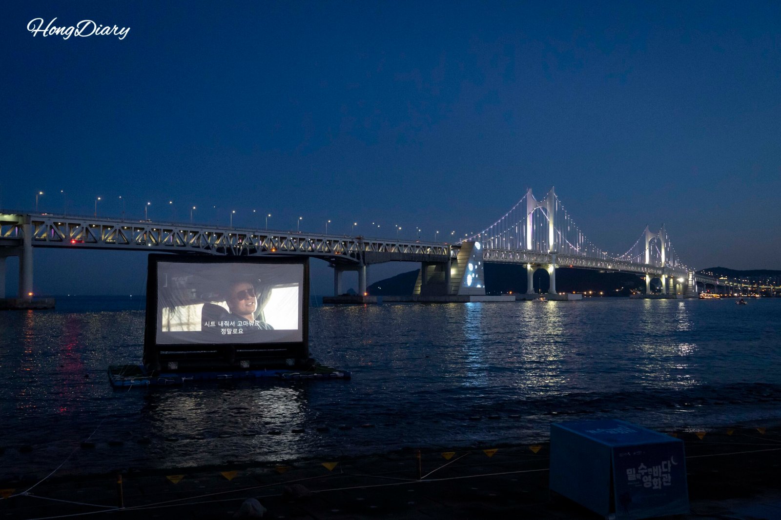 夜のミルラク水辺バダ映画館。広安大橋がフルライトアップされたスクリーン越しの景色