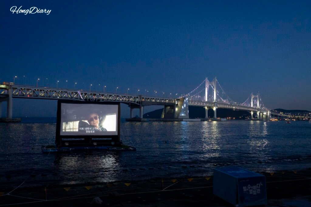 Millak Ocean Cinema de noche con el Puente Gwangan completamente iluminado al fondo