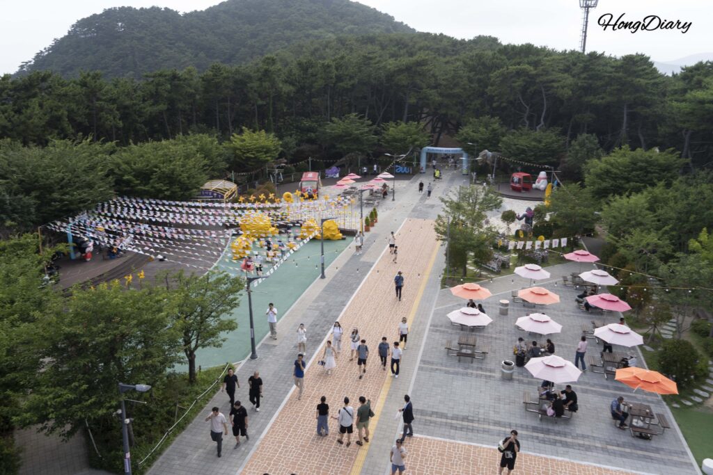 松島スカイパークのパークスクエア広場を屋上から見た風景。恐竜の彫刻や休憩スペースが点在（釜山）