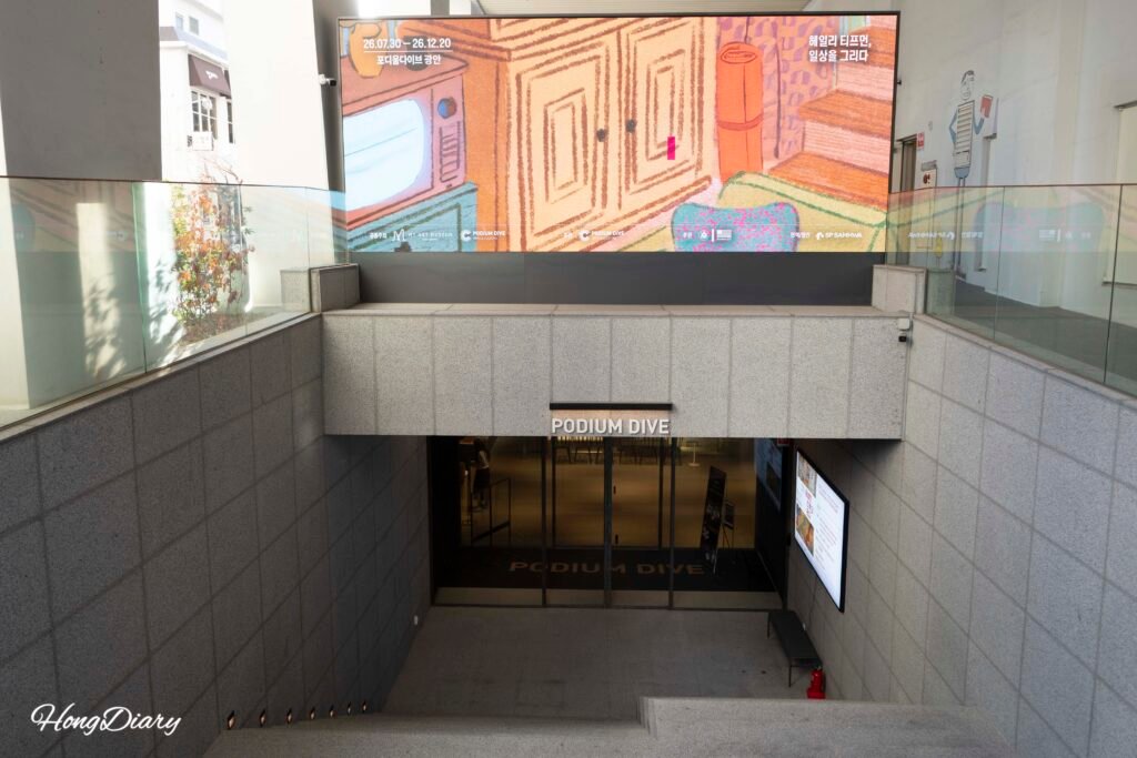 Entrance staircase leading underground to Podium Dive Gwangalli with large digital screen signage