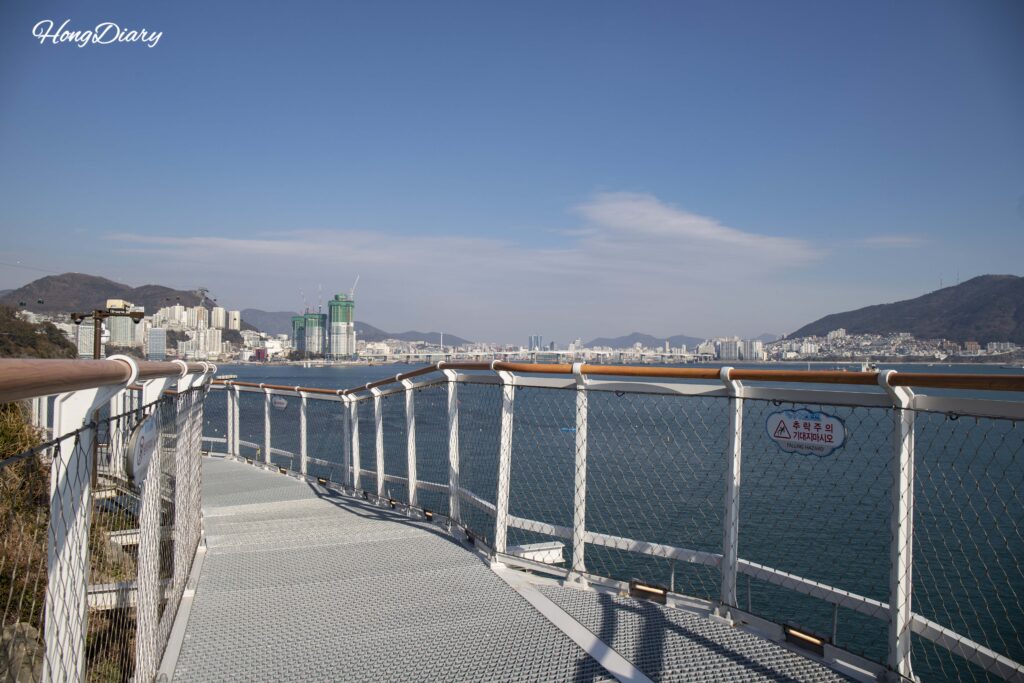 Personas caminando sobre el Puente Yonggung Songdo con el mar abierto debajo, Busan