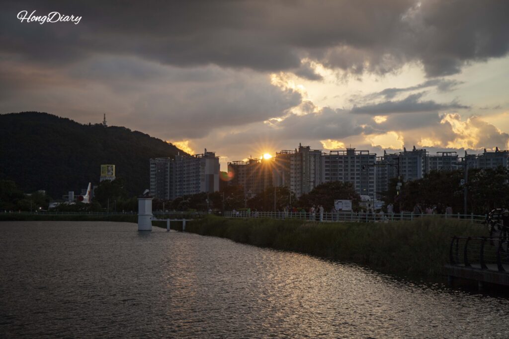 Cielo al atardecer sobre Suseongmot con siluetas de caminantes en el sendero
