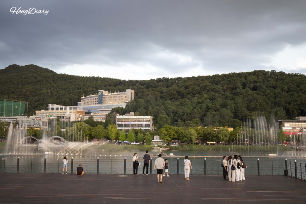 Panoramic view of Suseongmot lake with surrounding mountains and cafes in Daegu