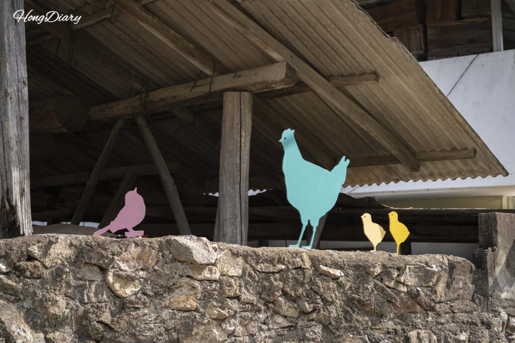 Mural de una gallina con pollitos pintado en una pared de un pueblo cerca del Valle Binggye