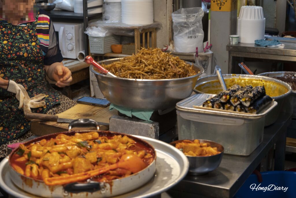 Burdock kimbap vendor at Seongdong Market Gyeongju with stacks of braised burdock root and freshly rolled kimbap