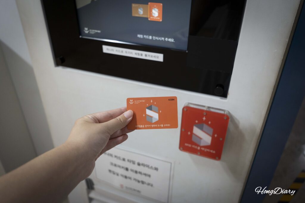 Visitante tocando la tarjeta RFID en un lector naranja en una estación de experiencia