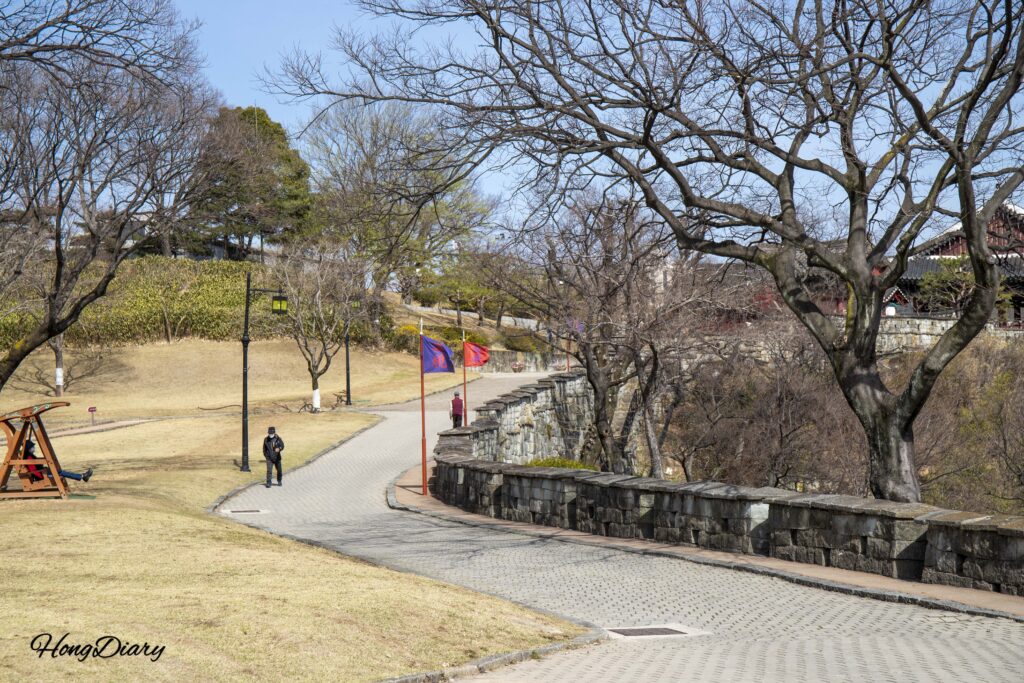 Personas caminando junto a la muralla de piedra de la Fortaleza de Jinju