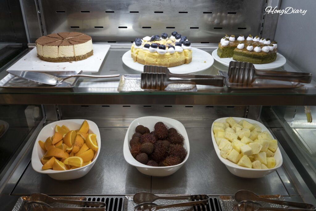 Dessert and fruit station with tiramisu, egg tarts, and tropical fruit at Ristorante, Hotel Nongshim Busan
