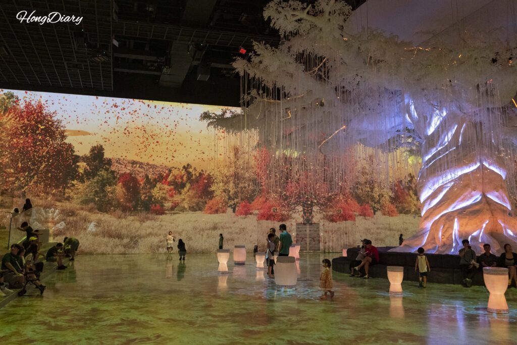 Visitors resting under the Sky Pillar tree during the autumn season projection at Flashback Gyerim in Gyeongju