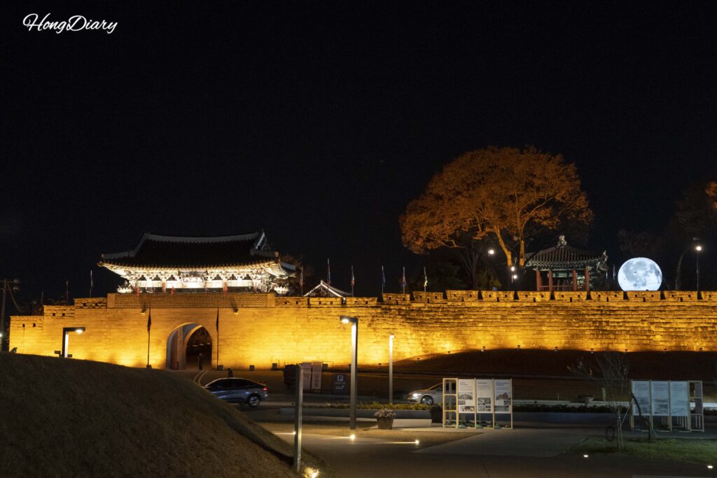 Murallas de la Fortaleza de Jinju iluminadas de noche, reflejándose sobre el río Namgang