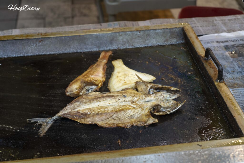 Fish being grilled on a charcoal grill at a Haeundae Traditional Market restaurant