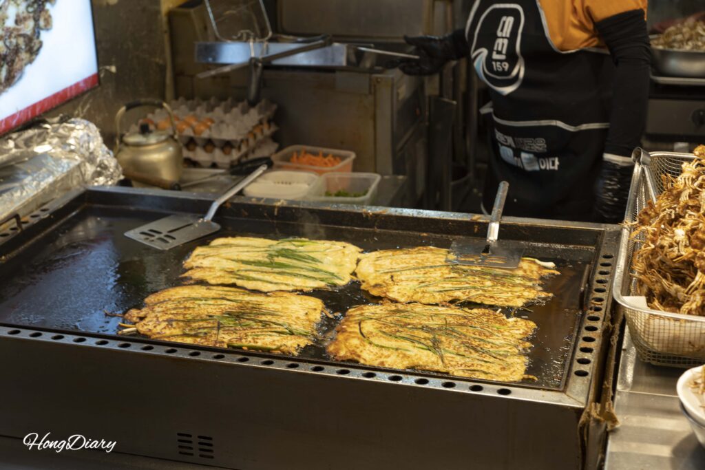 Korean jeon being fried on a large griddle at Haeundae Traditional Market