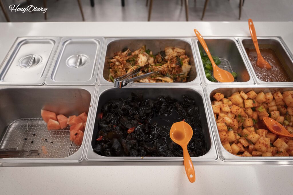 Estación de autoservicio con arroz blanco, fruta y acompañamientos adicionales en Irojeong Gumi