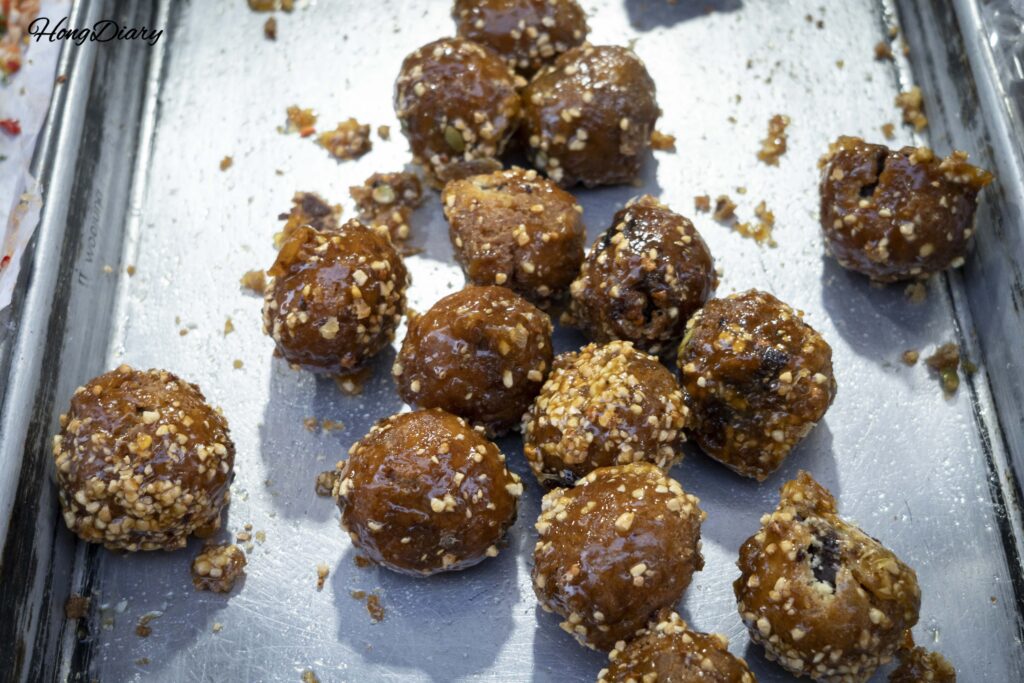 Close-up of Jinju-style kkulppang (honey bread) coated in syrup, peanut powder, and sesame seeds