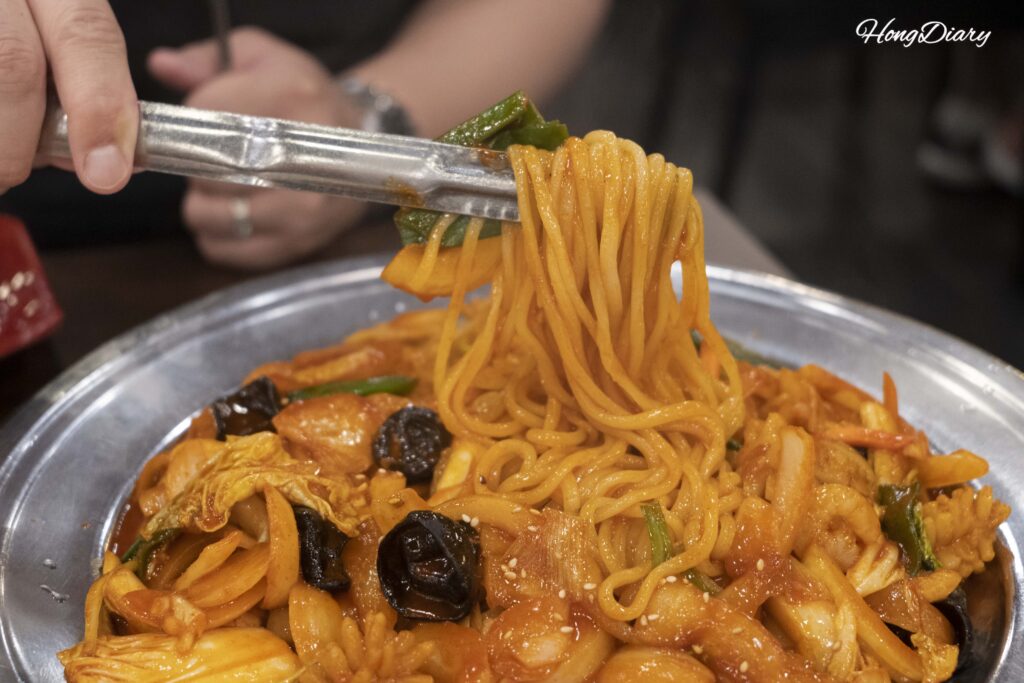 Levantando fideos de yakiudon con pinzas en el Restaurante Lian en Daegu