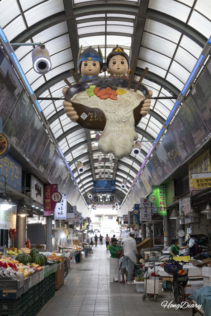 Interior del Mercado Seongdong en Gyeongju con tiendas, residentes locales y visitantes recorriendo los pasillos cubiertos