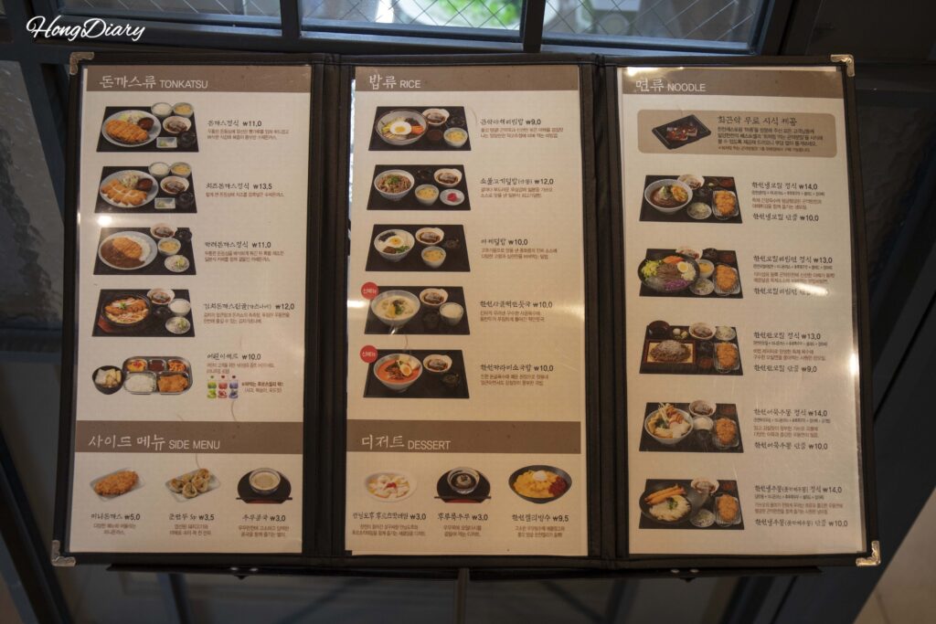 Full menu board at Restaurant Majung showing tonkatsu, rice, noodle, and dessert options at the Miryang Agar Theme Park