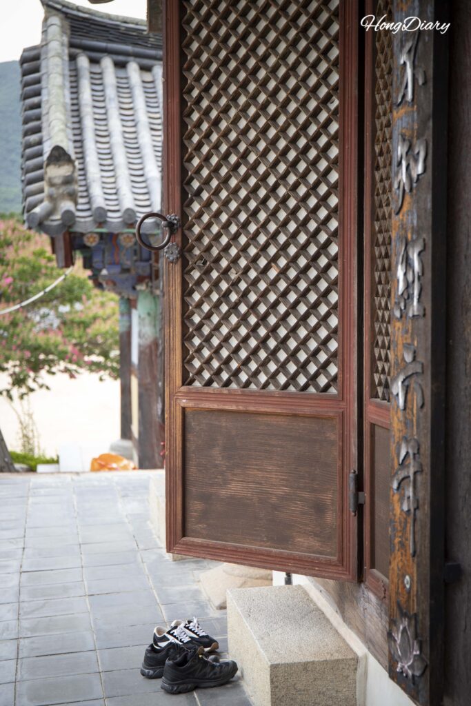 Entrada del Daegwangjeon con zapatos de visitantes alineados en la puerta del templo Pyochungsa