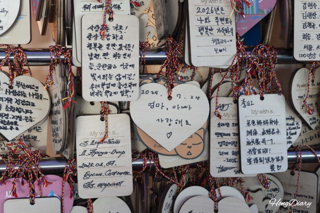 Pared cubierta con tarjetas de deseos escritas en múltiples idiomas en el piso 99 de Busan X the Sky
