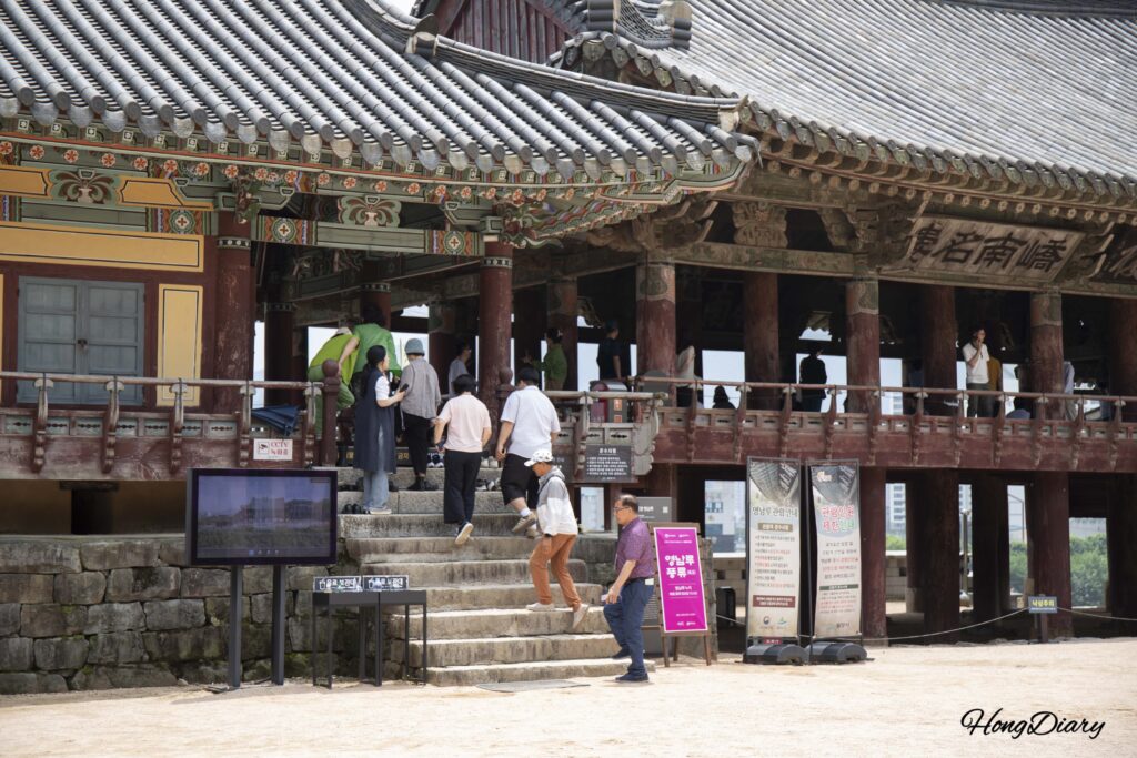 Visitors removing shoes and stepping onto the floor of Yeongnamnu Pavilion in Miryang
