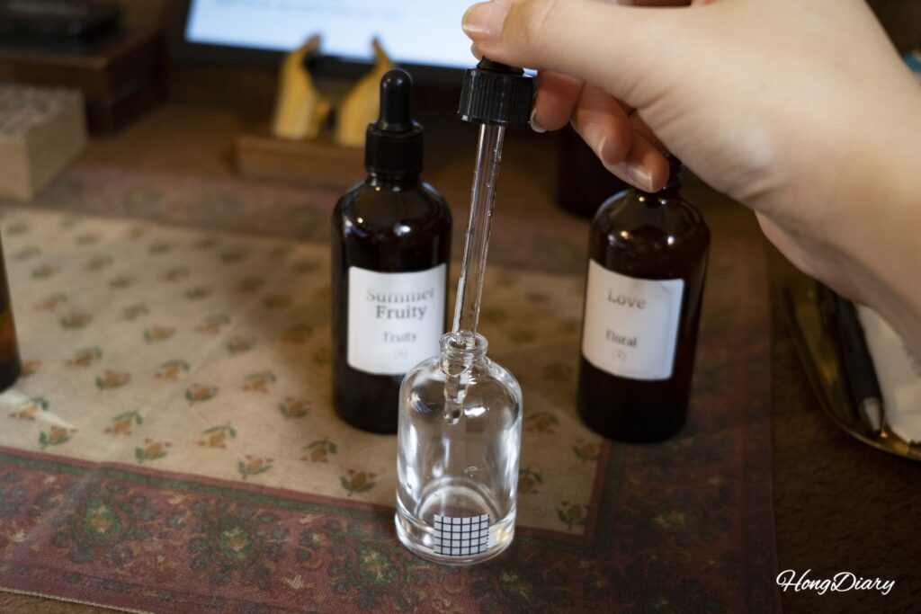Manos mezclando aceites aromáticos en un frasco vacío durante el taller de perfumes en Gwangalli