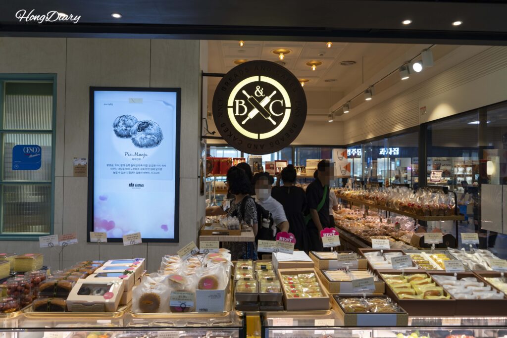 Clientes seleccionando pan en la Panadería B&C dentro de la Estación de Busan