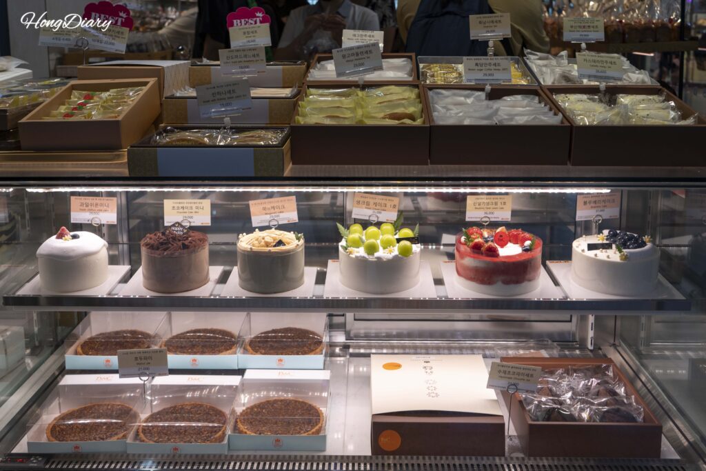 Whole cakes, walnut pies, and various gift set boxes on display at B&C Bakery Busan Station
