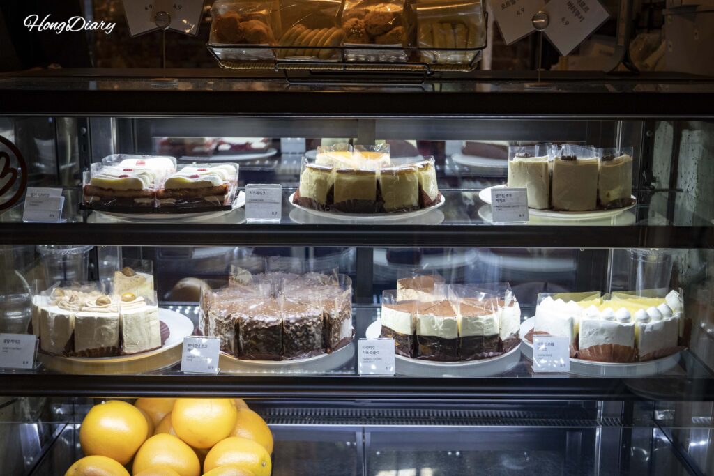 ブラウンハンズ百済のショーケースに並ぶティラミス、チーズケーキ、ヘーゼルナッツチョコケーキ（各₩8,900）
