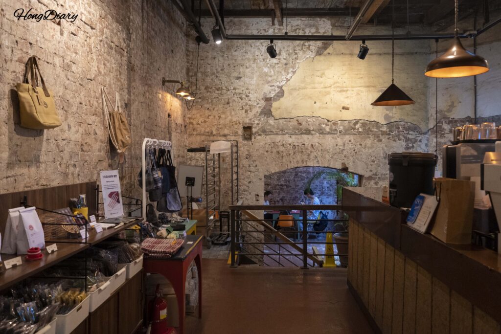 Customers seated inside Brown Hands Baekje cafe with goods display in the foreground, Busan