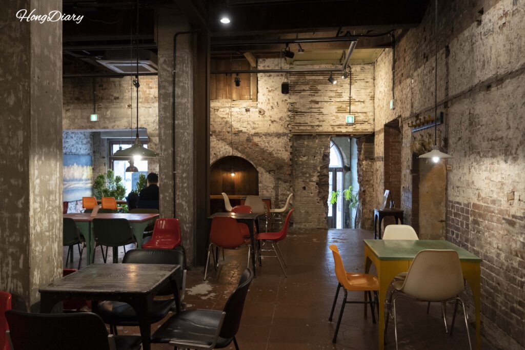 Vintage interior of Brown Hands Baekje cafe with rough plaster walls, wooden window frames, and warm lighting in Busan
