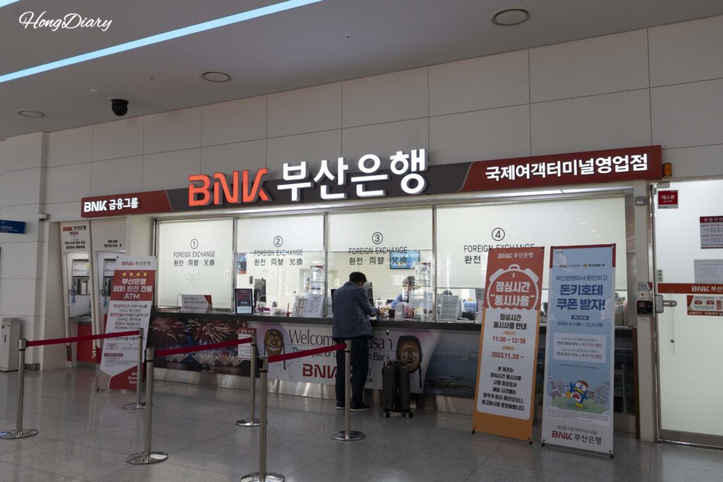 Busan Bank branch on the 2nd floor of Busan ferry terminal with a traveler exchanging currency at the counter
