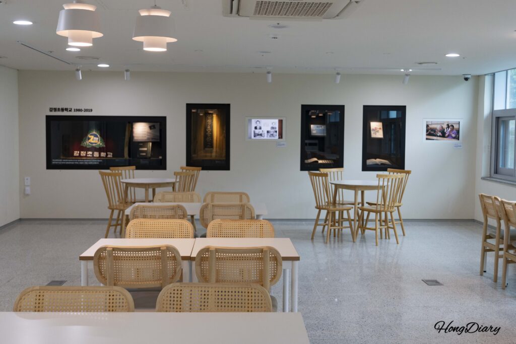 Exhibit on the history of Gamjeong Elementary School at the Busan Education History Museum, with seating area for visitors
