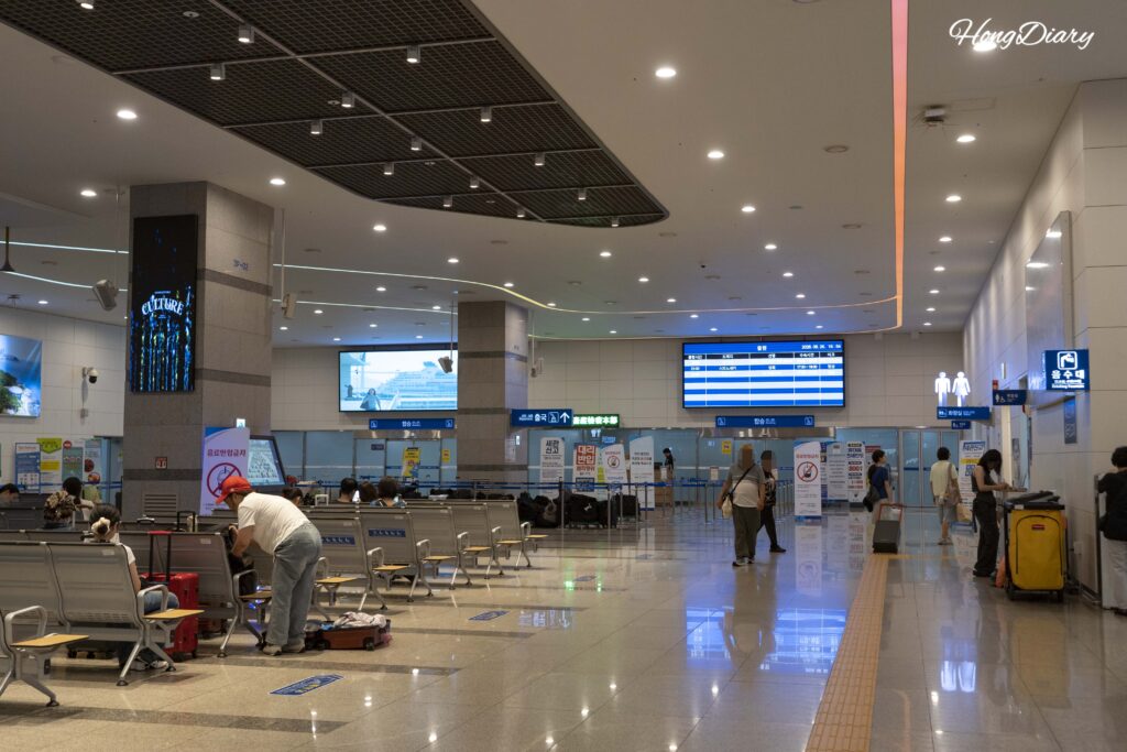 Crowded 3rd floor departure area at Busan Port International Passenger Terminal with travelers waiting near ticket counters