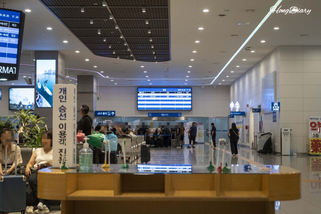 Departure hall on the 3rd floor of Busan ferry terminal crowded with passengers, with boarding document counters visible in the foreground