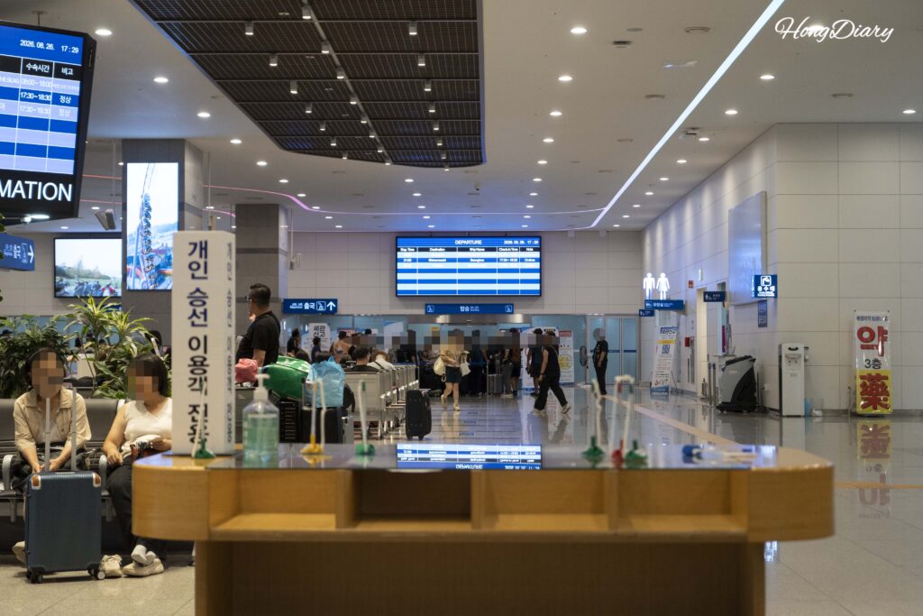 Vista general del tercer piso de salidas de la terminal de ferris de Busan lleno de pasajeros, con documentos de embarque visibles