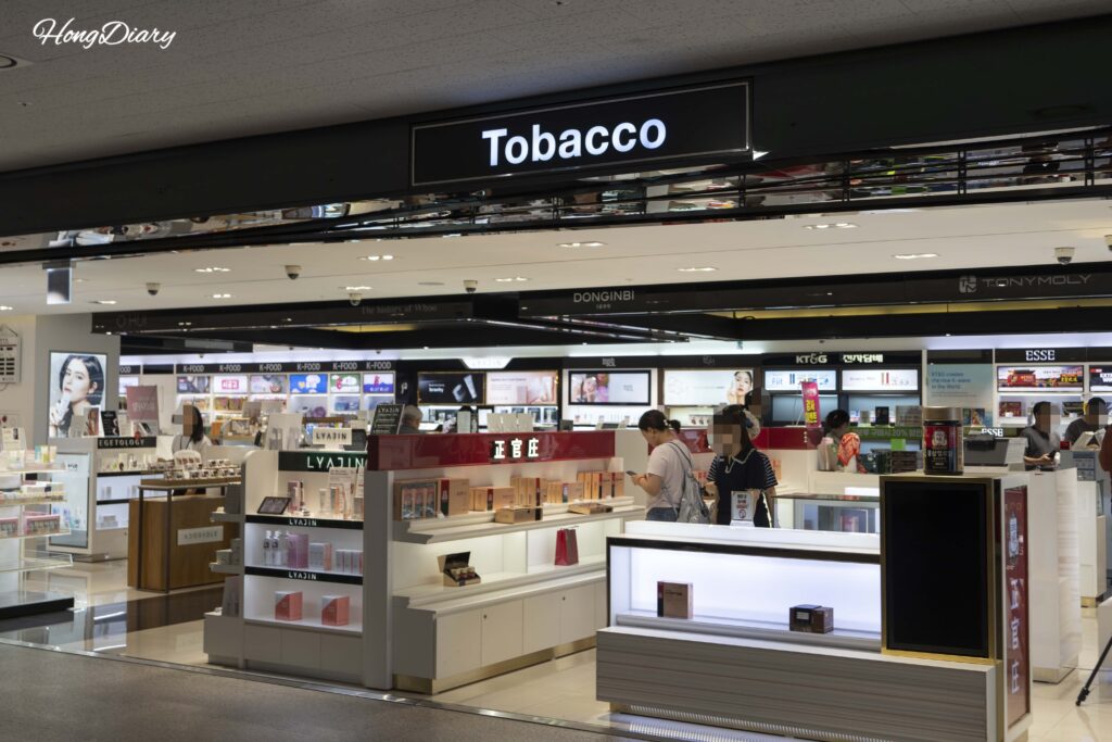 Zona de tienda duty-free dentro de la terminal de ferris de Busan después del control de emigración, con pasajeros comprando