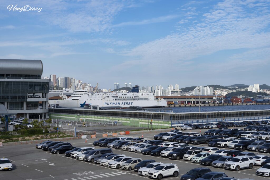 Exterior de la terminal internacional de ferris de Busan con estacionamiento y un ferry hacia Fukuoka atracado en el muelle