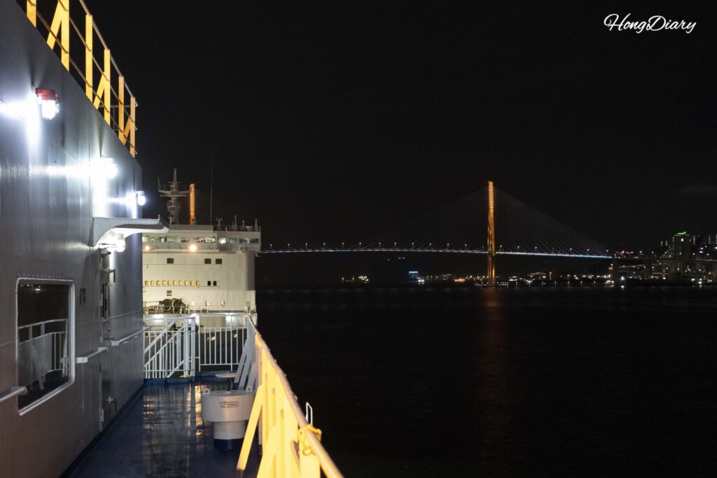 Busan Harbor Bridge illuminated at night seen from the deck of the Seonghee ferry
