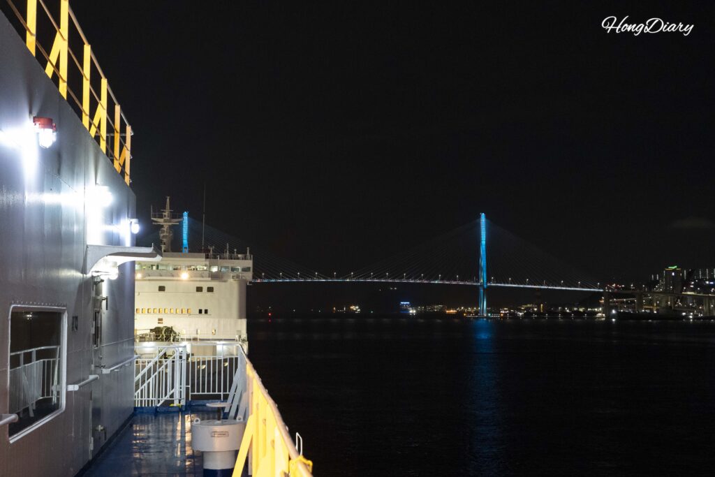 Puente del Puerto de Busan iluminado de noche visto desde la cubierta del ferry Seonghee