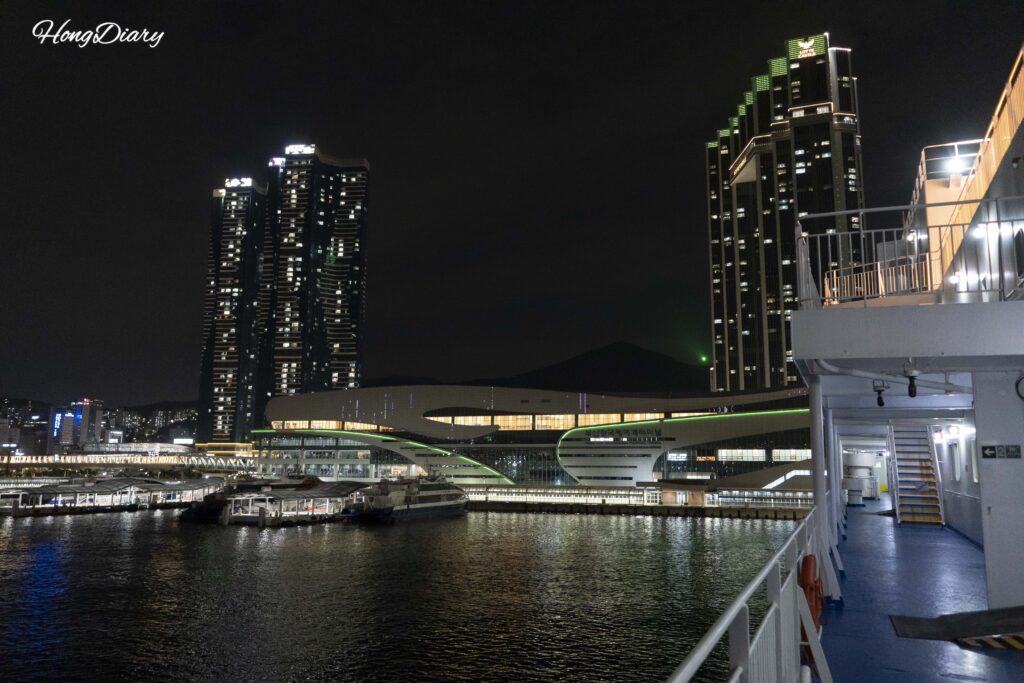Skyline nocturno del Puerto de Busan y edificios de la terminal vistos desde la cubierta del Seonghee