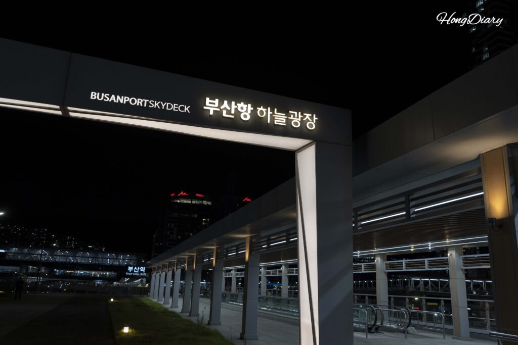 Busan Port Sky Plaza (Haneul Gwangjang) at dusk, overlooking North Port Waterfront Park below