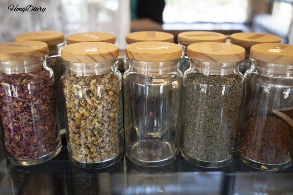 Frascos de vidrio con hojas de té secas y pétalos de flores en el café hanok Byeotnwi de Miryang